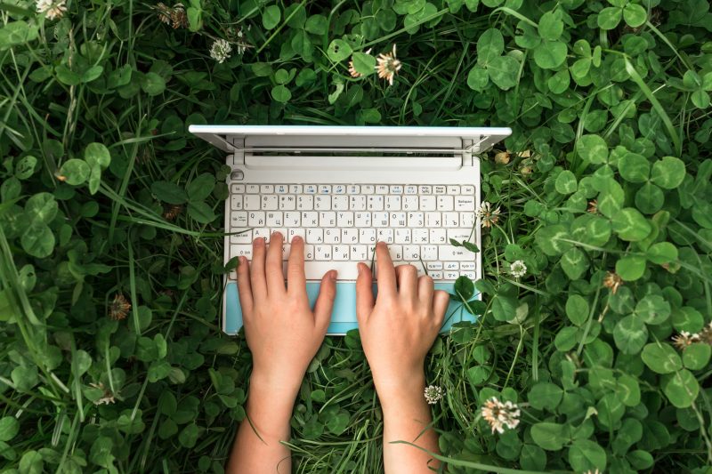 Kid typing on computer outside