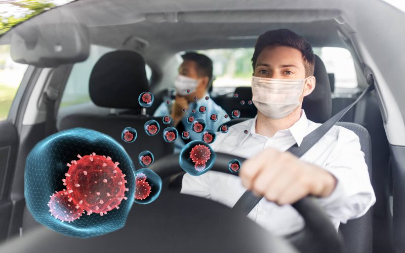 Rideshare driver wearing facemask with passengers in the back, coronavirus floating in air